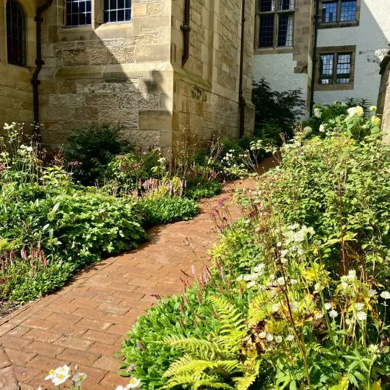 Plants line the red brick path